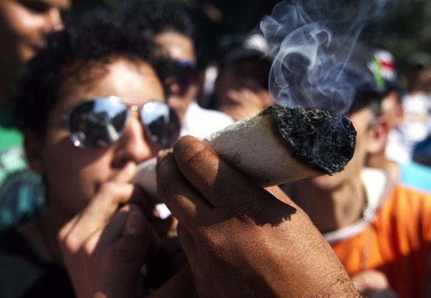 Мужчина курит косяк во время демонстрации в поддержку легализации марихуаны в Медельине, Колумбия.