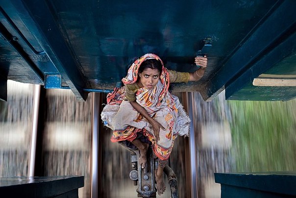 Женщина едет между вагонами местного поезда в северном направлении от Дакки, столицы Бангладеш. 