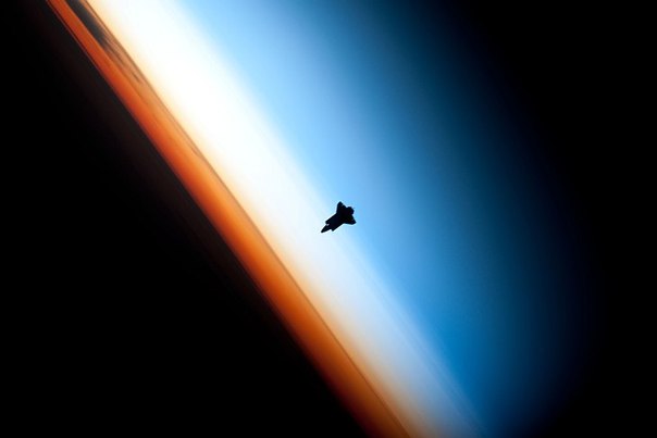 Силуэт STS-130 на фоне красочного горизонта Земли.