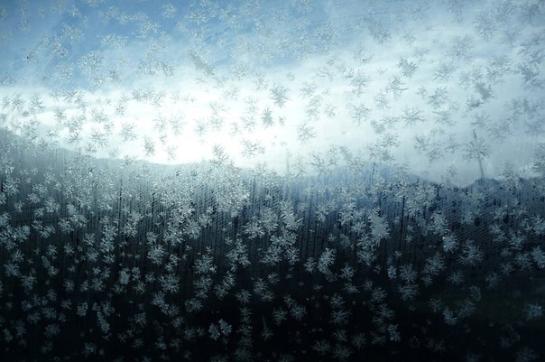 Заледеневшие снежинки на боковом стекле автомобиля во время путешествия к склонам для сноубординга. 