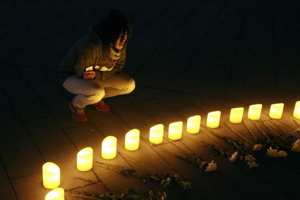 Люди зажигают свечи в память о жертвах взрывов на Бостонском марафоне в Олимпийском парке в Пекине, Китай, 16 апреля 2013 года.