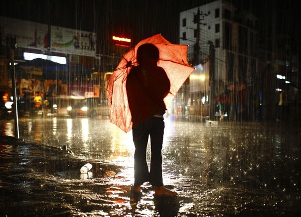 Девушка стоит под зонтом во время сильного дождя в Катманду, Непал.