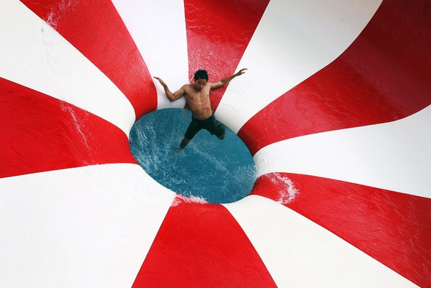 Мужчина катается с горки в бассейне в Лиме, Перу
