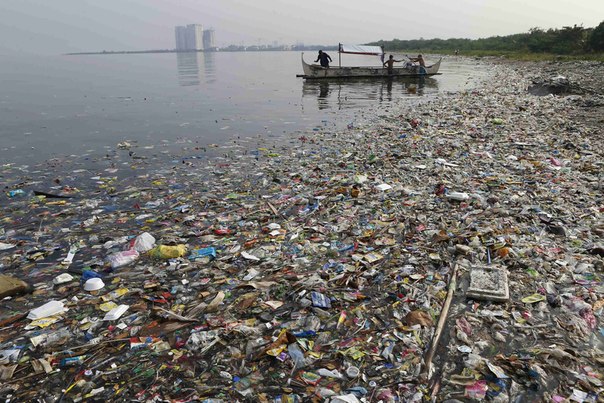 Рыбаки отплывают от берега в загрязнённом Манильском заливе, Филиппины.