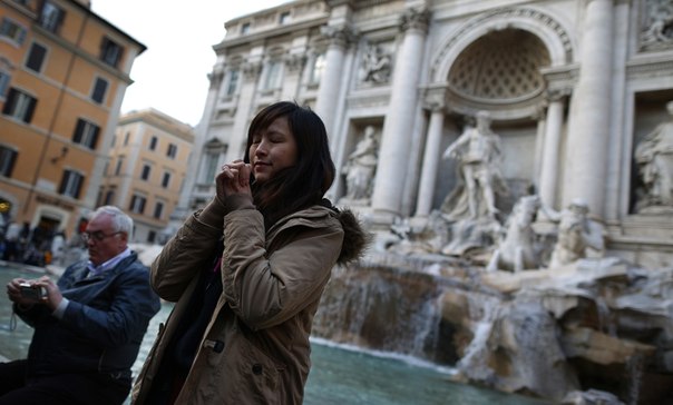 Женщина загадывает желание возле фонтана Треви в Риме, Италия.